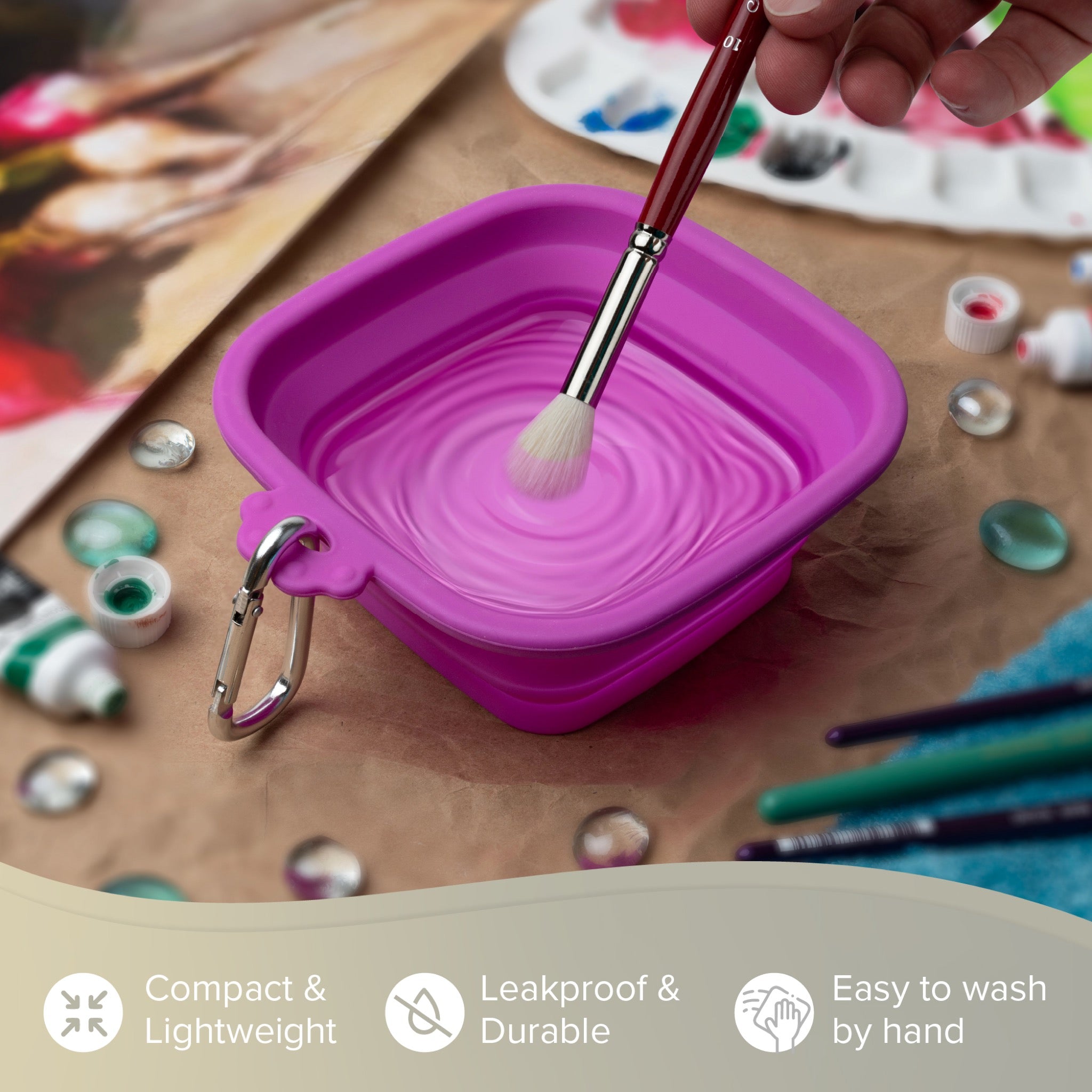 Purple collapsible container with a brush on a table with art supplies